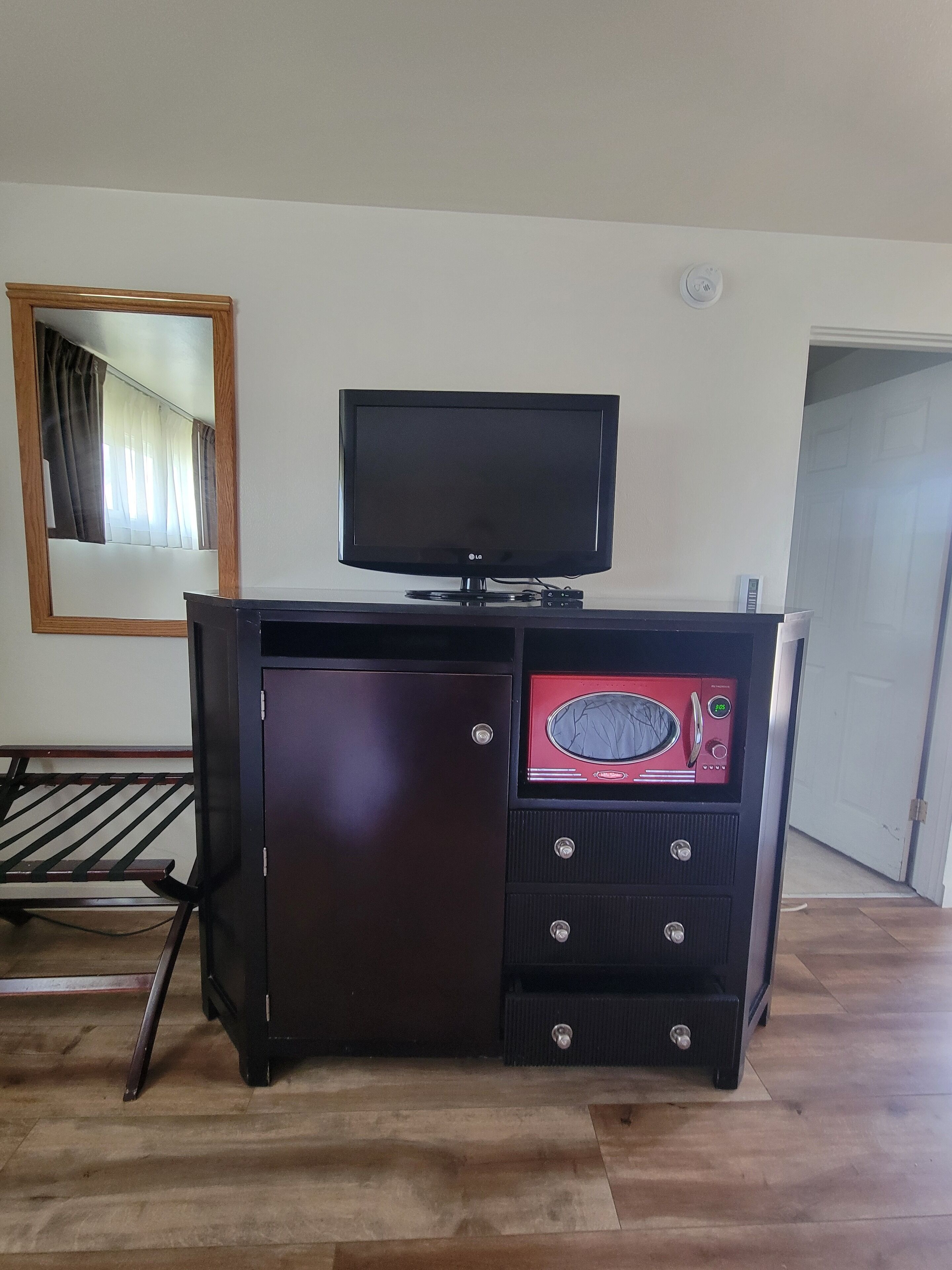 A room with a wooden cabinet, a flat-screen TV, and a microwave.