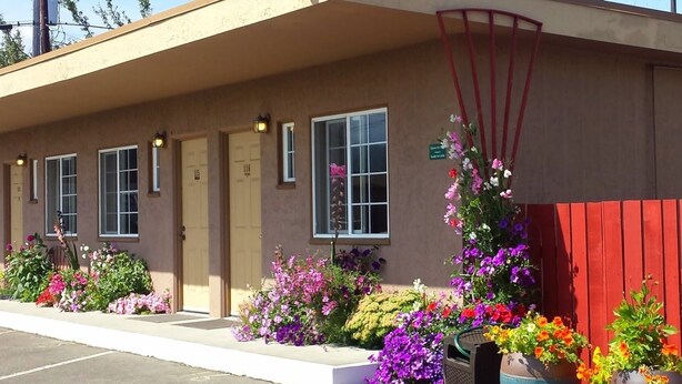 A motel with a beige exterior, three doors, and a red fence. - Uptown Inn (Port Angeles)
