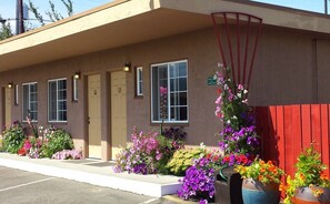 A motel with a beige exterior, three doors, and a red fence. - Uptown Inn (Port Angeles)
