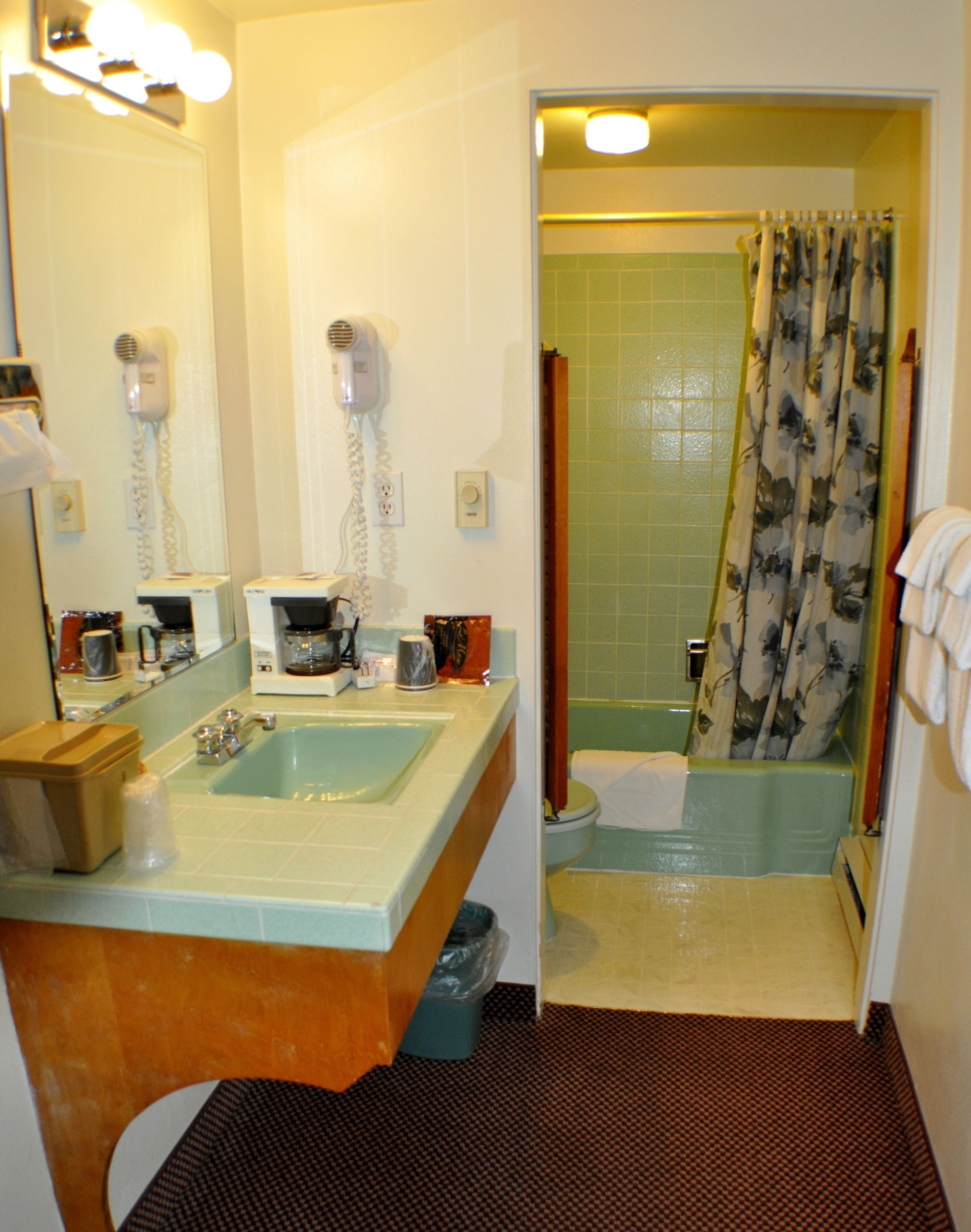 A bathroom with a sink, a hairdryer, and a shower.