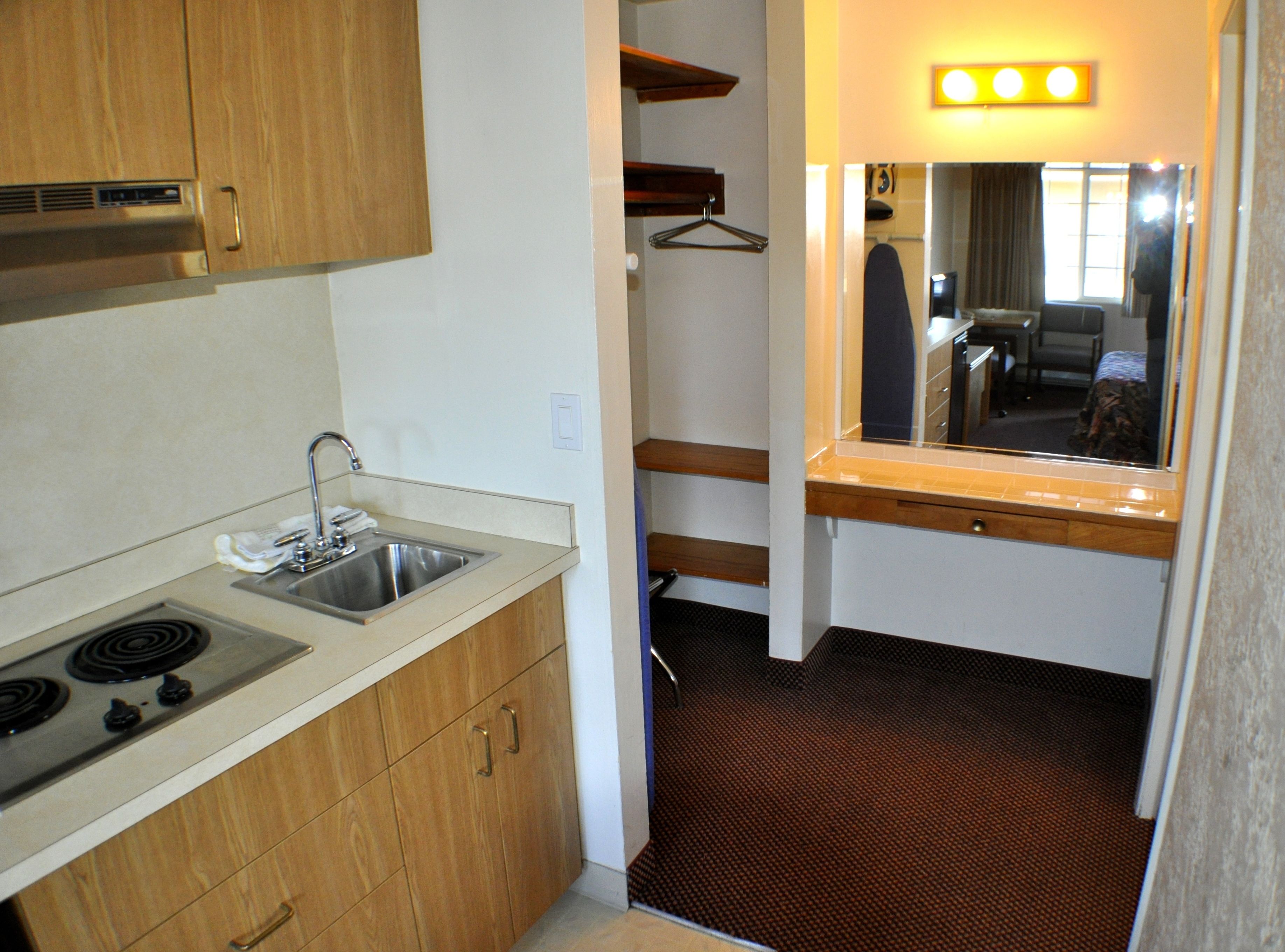A compact kitchen with a sink, stove, and wooden cabinets.