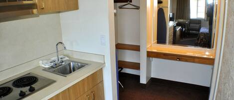 A compact kitchen with a sink, stove, and wooden cabinets.