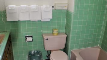 Casa de banho com sanita, lavatório e banheira. As paredes e o chão têm azulejos verdes.