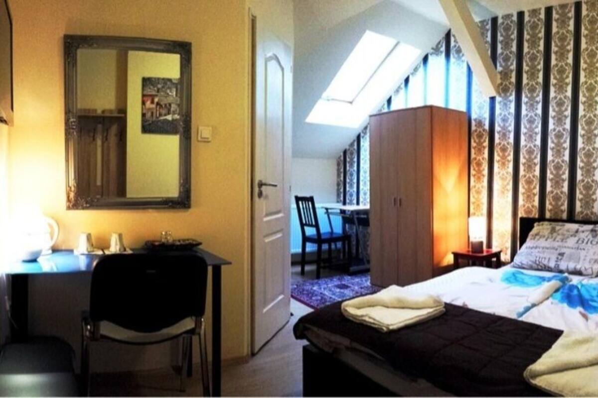 A bedroom with a bed, a desk, a chair, a wardrobe, and a skylight.