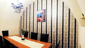 Ein Essbereich mit einem Holztisch, schwarzen Stühlen, einer Vase und einer Wand mit strukturierter Tapete und einem gerahmten Bild.
