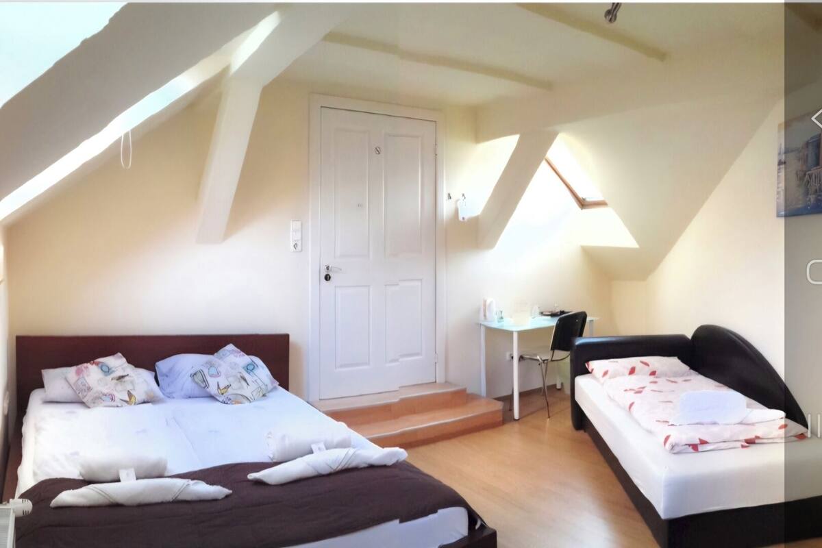 A bedroom with a bed, a desk, and a chair. There is a door and a window.