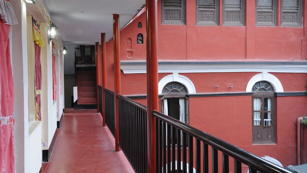 A corridor with a red wall, a staircase, and a railing. - Hotel Himalaya Yoga (Kathmandu)