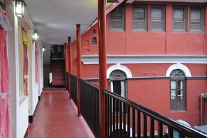 Un pasillo con pared roja, una escalera y barandilla.