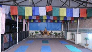 A meditation area with prayer flags, a statue, and yoga mats. - Hotel Himalaya Yoga (Kathmandu)