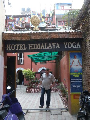Un hombre está de pie frente a un edificio con un letrero que dice "HOTEL HIMALAYA YOGA".