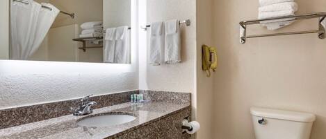 A bathroom with a granite sink, a toilet, a towel rack, and a mirror.