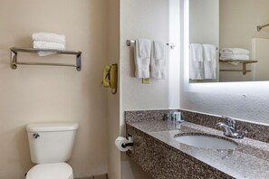 Un baño con inodoro, lavamanos y perchero para toallas.