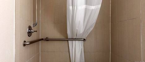 A bathroom with a shower area, a grab bar, and a small step stool.
