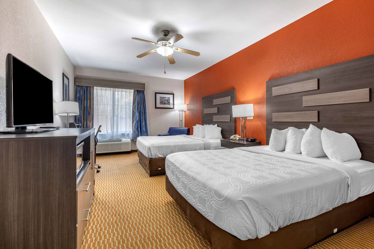 Une chambre d’hôtel avec deux lits, une télévision, un bureau et un ventilateur de plafond.