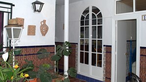 Una habitación con piso de baldosas, una puerta blanca, un ventanal con vistas y una planta en maceta.