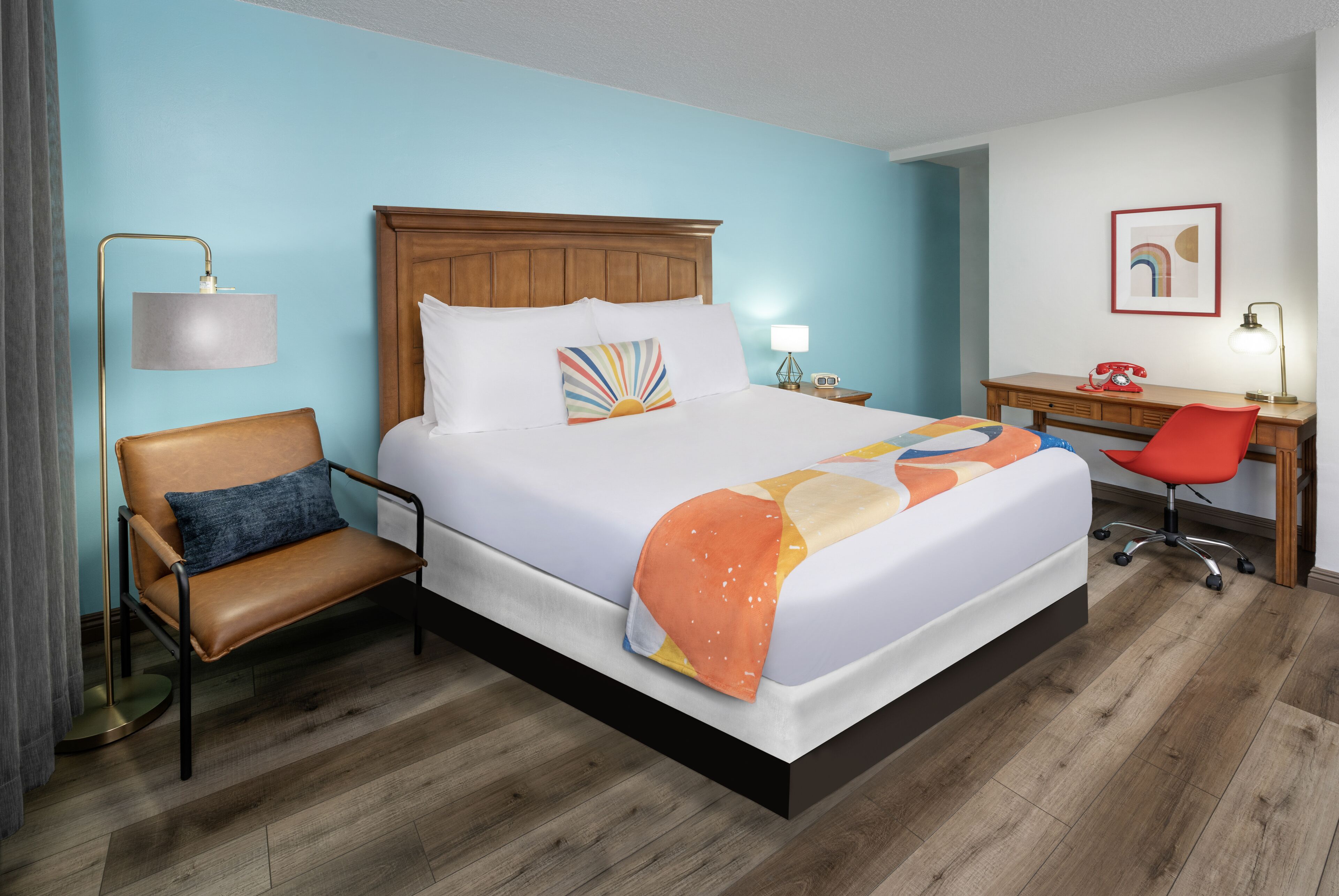 Una habitación de hotel con una cama grande, un escritorio, una silla y una lámpara.