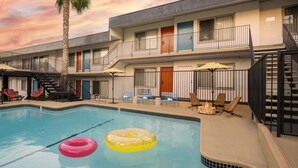 A hotel with a swimming pool, outdoor seating, and a palm tree. - The Sojourn Los Angeles - Sherman Oaks (Sherman Oaks)