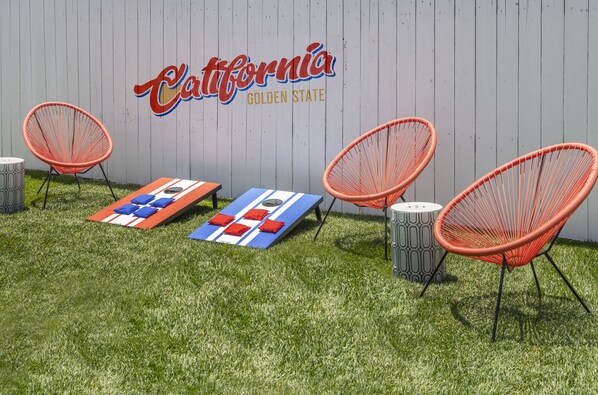 Un patio con un mural al estilo californiano, dos sillas anaranjadas y un tapete colorido.