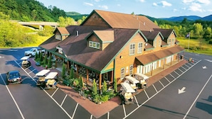 A lodge with a large parking area, multiple golf carts, and a scenic mountain backdrop.