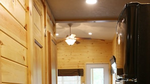 A wooden interior with a kitchen area, including a refrigerator, stove, and cabinets.