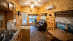 A cozy cabin interior with a kitchen, dining area, and a sofa.