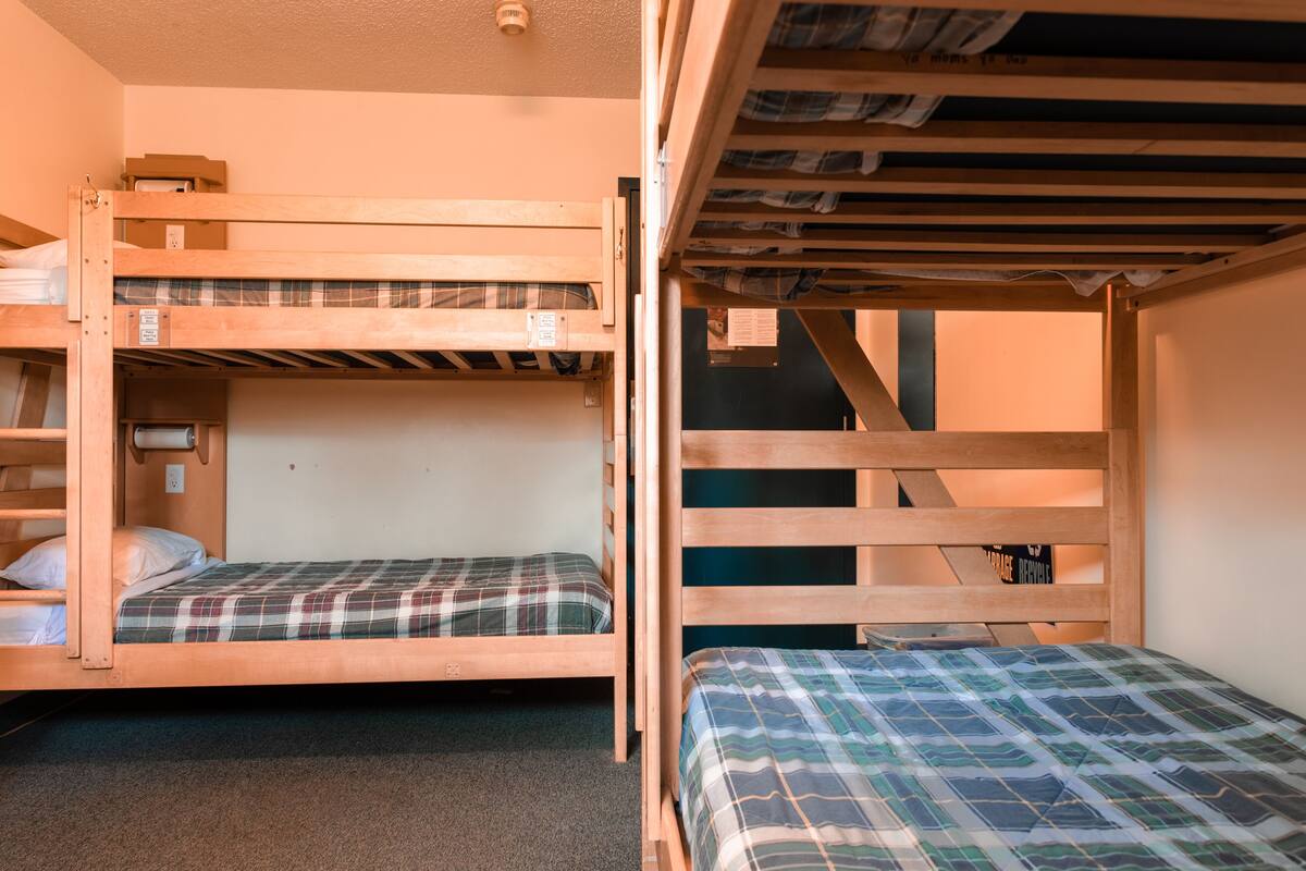 Une chambre de dortoir avec des lits superposés, un petit bureau et une chaise.