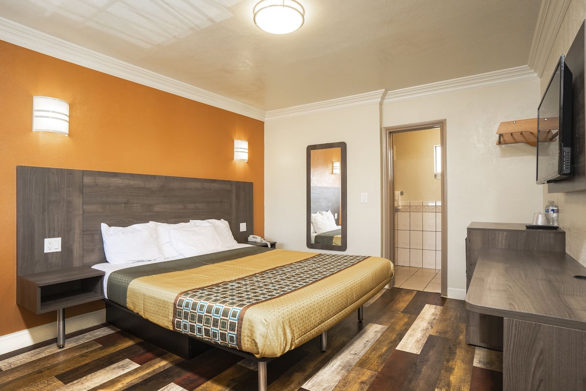 A hotel room with a bed, bedside table, and a desk with a chair.