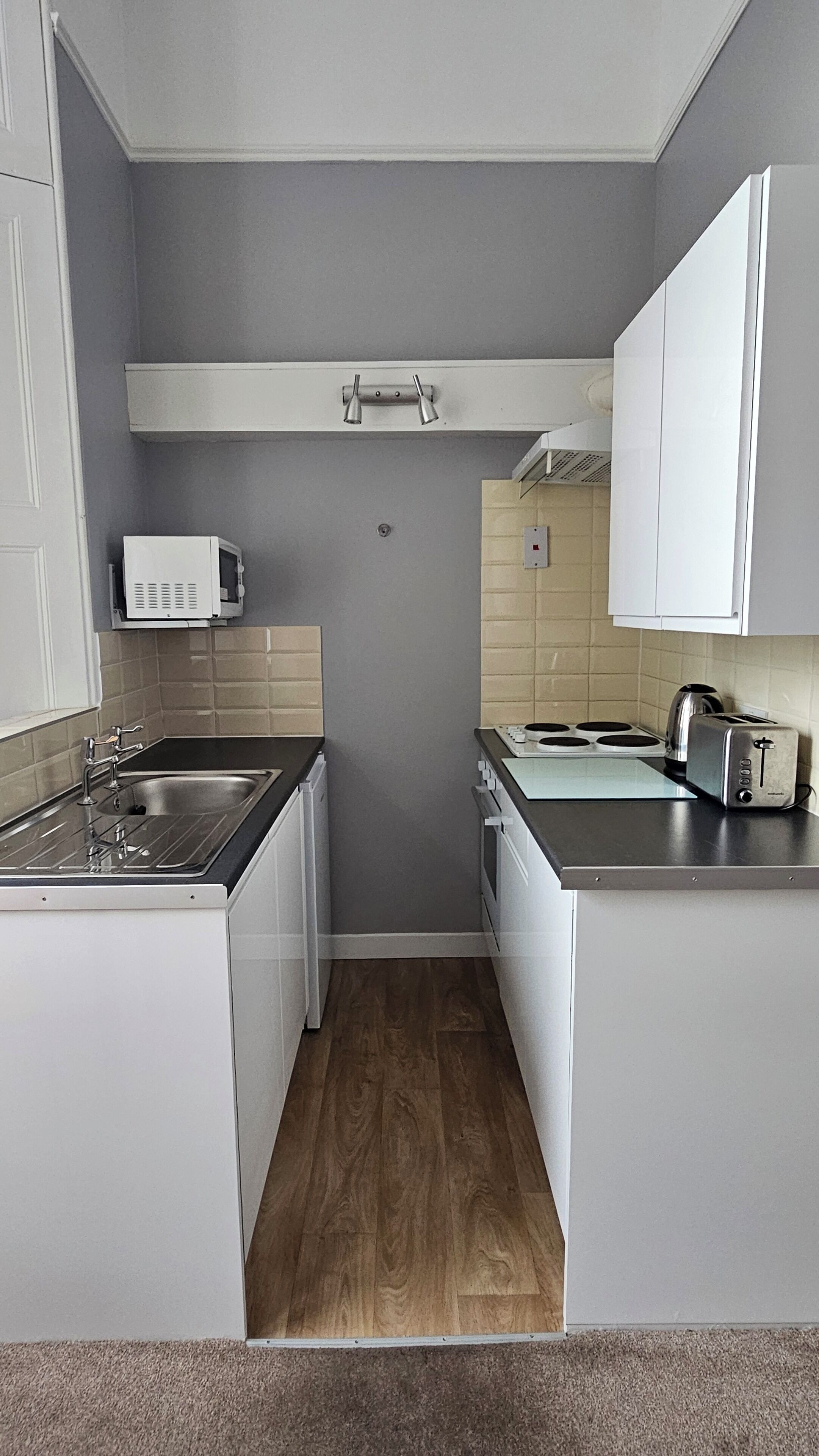 A compact kitchen with a sink, stove, and toaster.