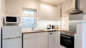 Una cocina moderna con armarios blancos, microondas integrado, campana extractora de acero inoxidable y lavavajillas.