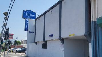 Un edificio con el letrero del Hollywood Value Inn, un motel con el número 5200, y una calle con coches y semáforos.