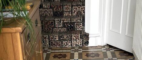 Esquina de una habitación con suelo de baldosas estampadas, un armario de madera y una puerta con la etiqueta 'Private'.