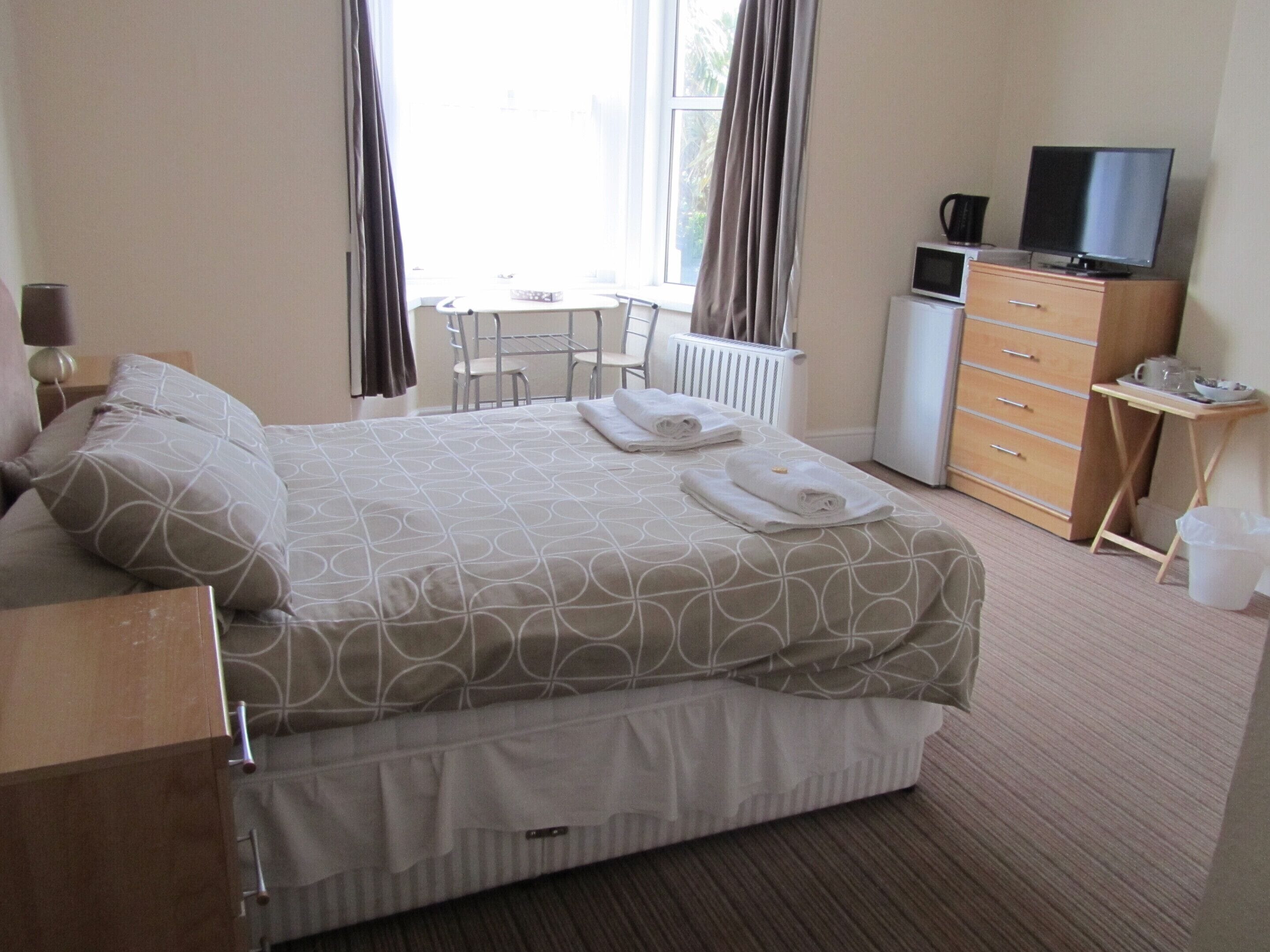 Une chambre d’hôtel équipée d’un lit, d’un bureau, d’une commode, d’une télévision et d’un radiateur.