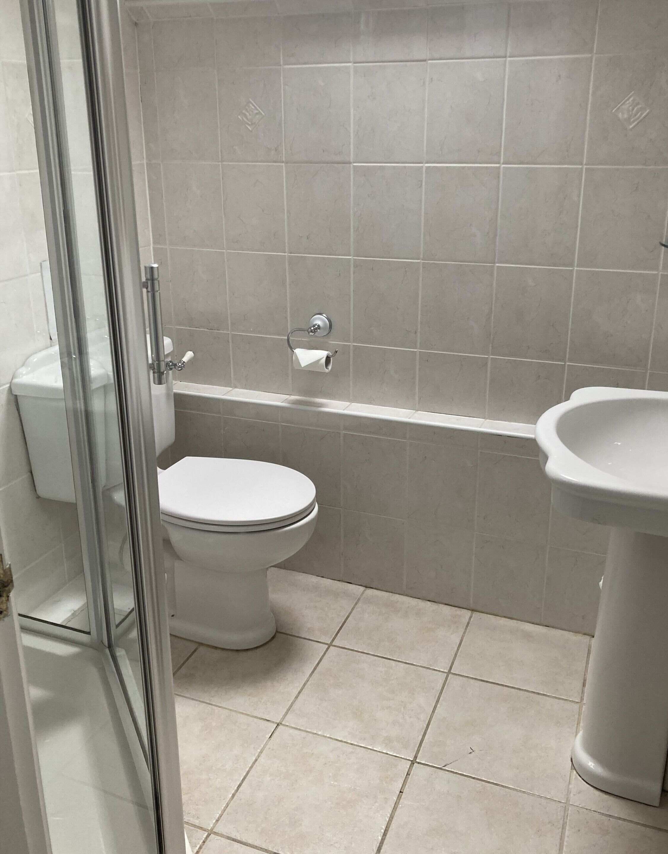 A bathroom with a toilet, a shower enclosure, and a sink.