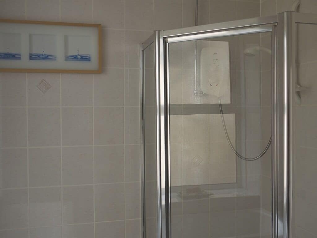 Une cabine de douche fermée par des parois en verre, dotée d’un panneau de commande et d’un porte-serviettes.