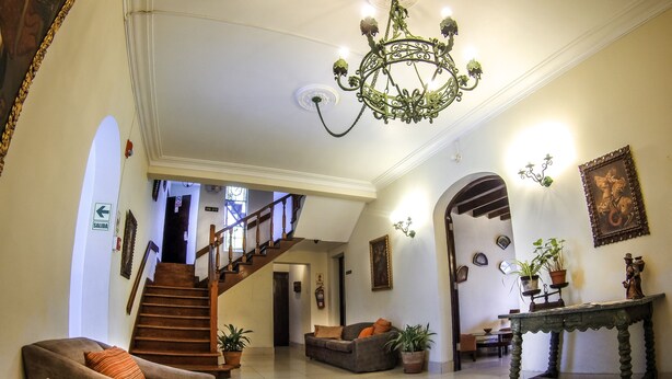 A spacious lobby with a chandelier, a staircase, and a seating area with sofas and potted plants. - Hotel Señorial (Lima)