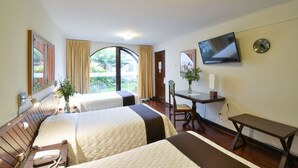 A hotel room with two beds, a desk, a TV, and a window with curtains. - Hotel Señorial (Lima)