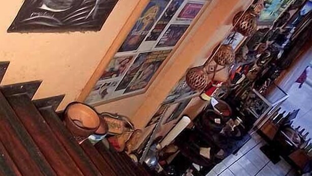 Una zona de bar con suelo de madera, una barra alta y varios botellas y vasos.