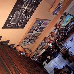 A bar area with wooden flooring, a high counter, and various bottles and glasses. - Hostal Del Este Santa Fe (San José)