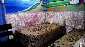 Una habitación con dos camas, una silla y un cuadro de paisaje en la pared.