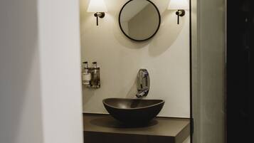 A modern bathroom with a black vessel sink, two wall-mounted lights, and a mirror.