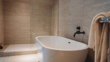A modern bathroom with a freestanding bathtub, a shower area, and a towel rack.
