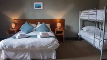 A hotel room with a single bed, a bunk bed, and two bedside lamps.