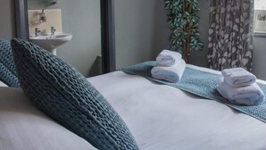 Habitació d'hotel amb un llit, un vàter, un mirall i una planta en test.