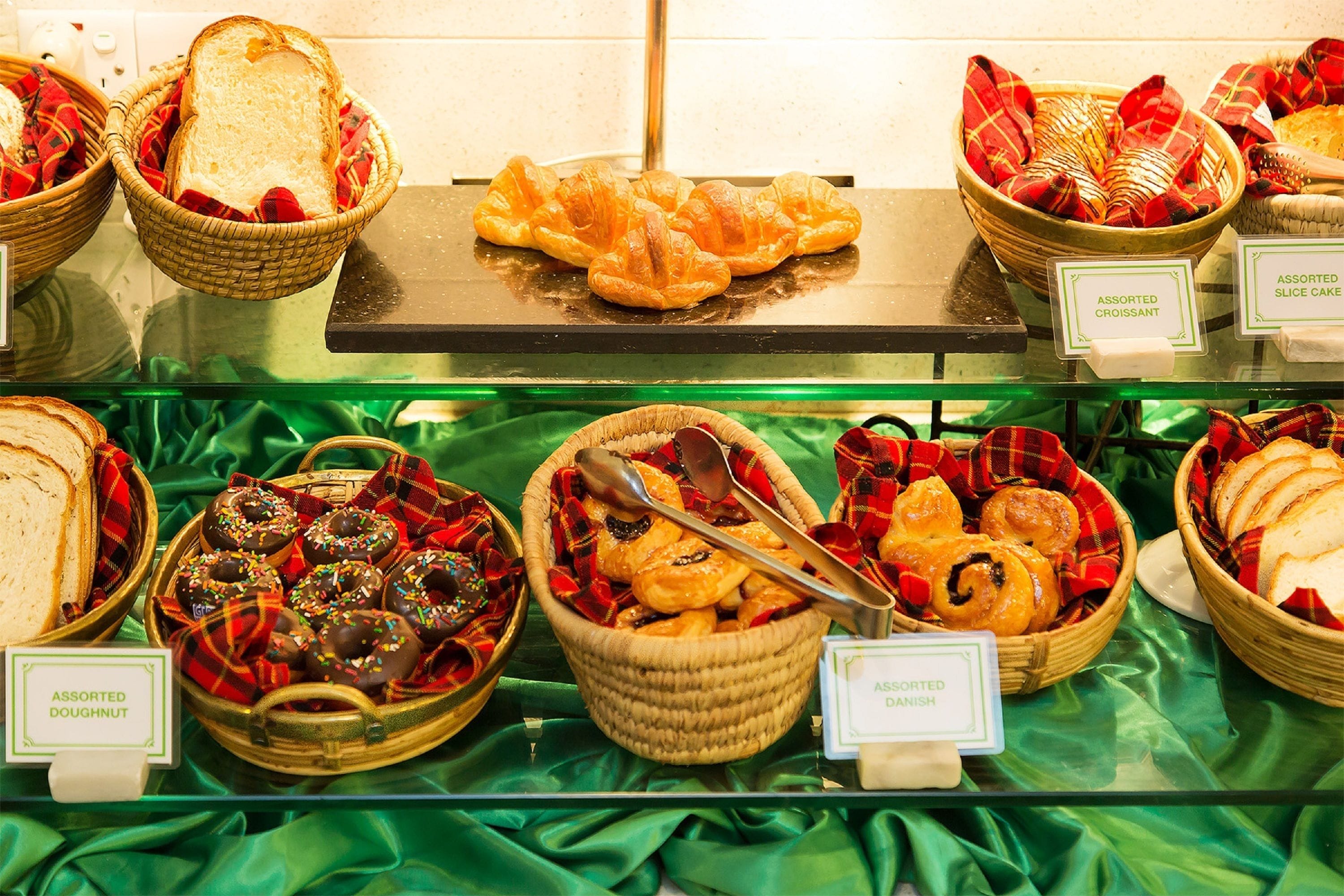 A display of assorted pastries and bread in baskets with labels.