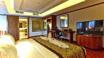 Habitación de hotel con una cama grande, un escritorio con silla, un televisor y un espejo.