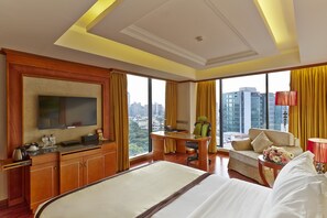 Habitación de hotel con una cama grande, un escritorio con silla, un sofá y un televisor.