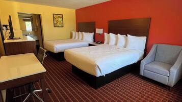 A hotel room with two beds, a desk, a chair, and a small table.