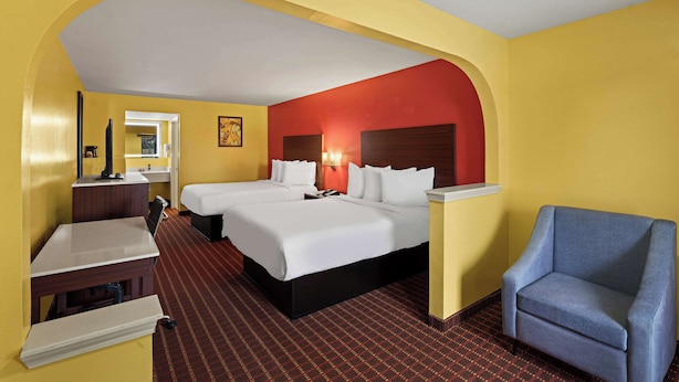 A hotel room with two beds, a desk, a chair, and a mirror. - SureStay by Best Western Gulfport (Gulfport)