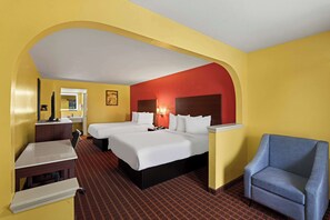 A hotel room with two beds, a desk, a chair, and a mirror.