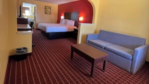 A hotel room with a bed, a sofa, a desk, and a trash bin. - SureStay by Best Western Gulfport (Gulfport)